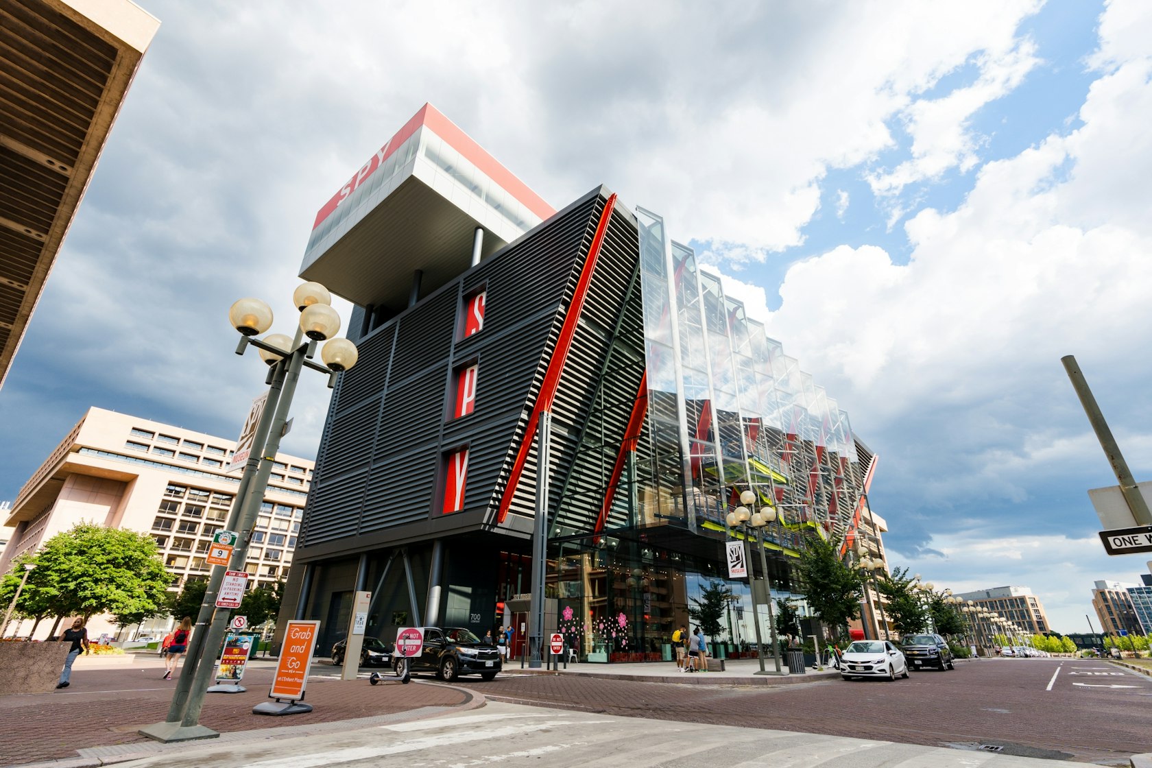 The modern exterior of the International Spy Museum in Washington, DC, featuring a striking design with red accents and glass panels under a cloudy sky.