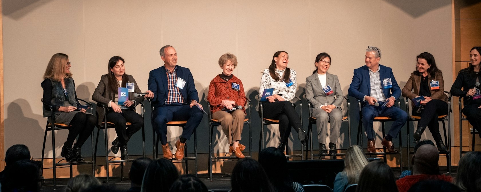 A stage of professional panelists smiling and laughing. 