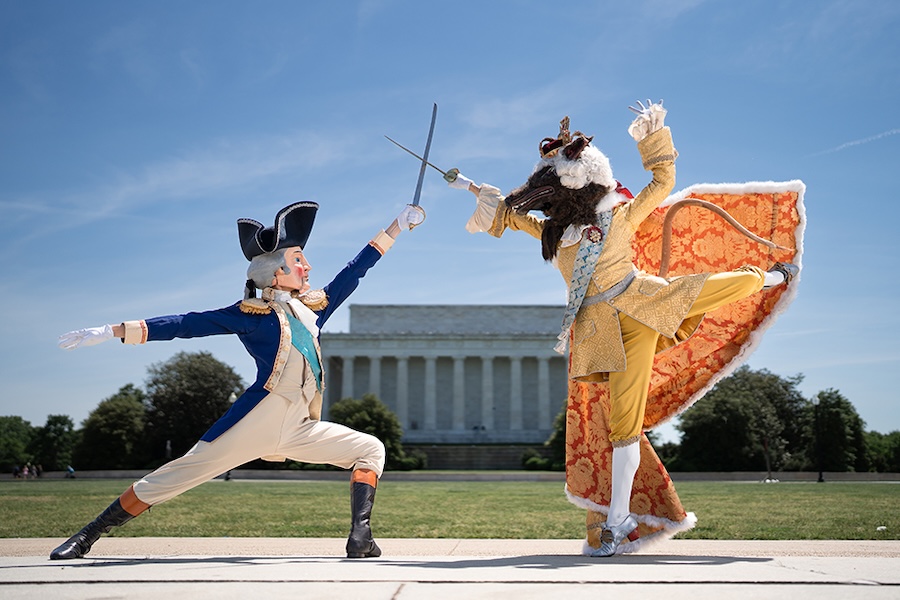 Two performers in elaborate Revolutionary War and animal-themed costumes duel with swords in front of the Lincoln Memorial.
