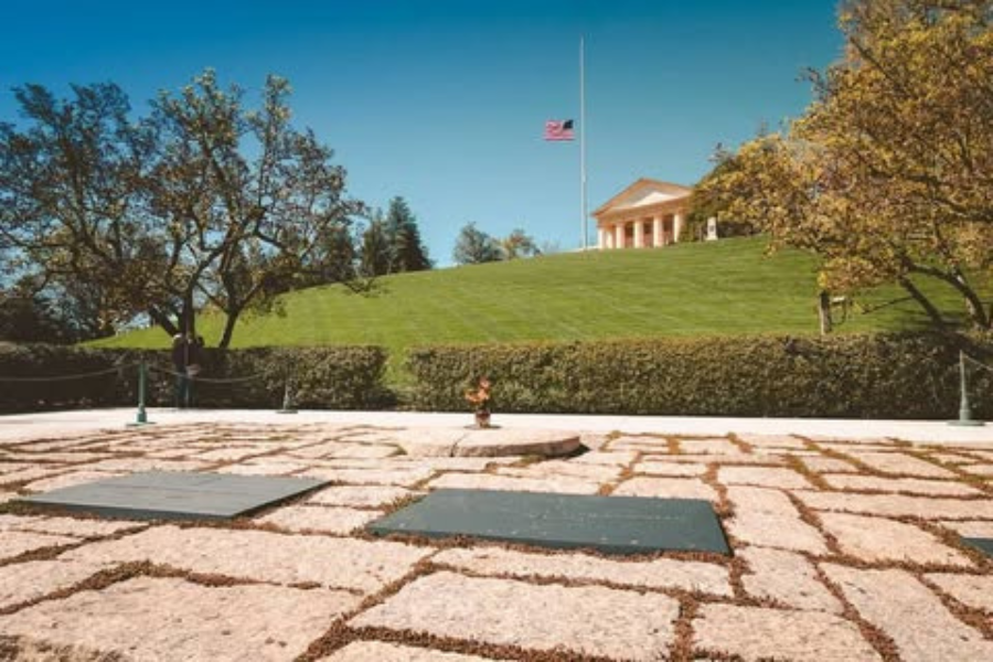 Gravesite of President John F. Kennedy at Arlington National Cemetery with eternal flame and Arlington House in the background.