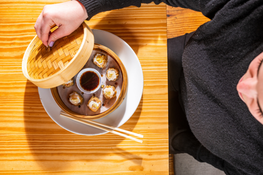 A diner lifts the bamboo lid on gold-topped siu mai dumplings at China Chilcano in Washington, DC.