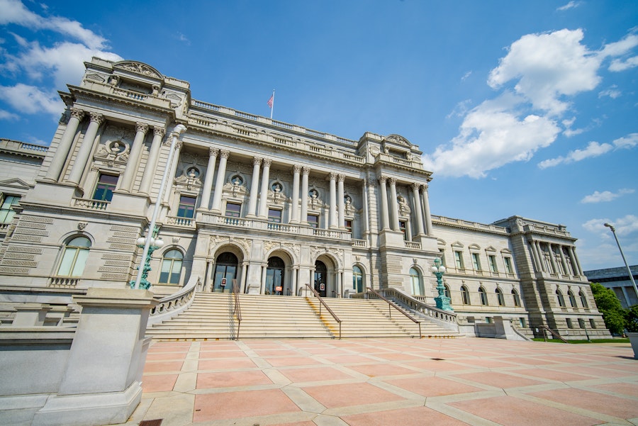 The neoclassical façade of the Library of Congress stands grandly beneath a bright blue sky.