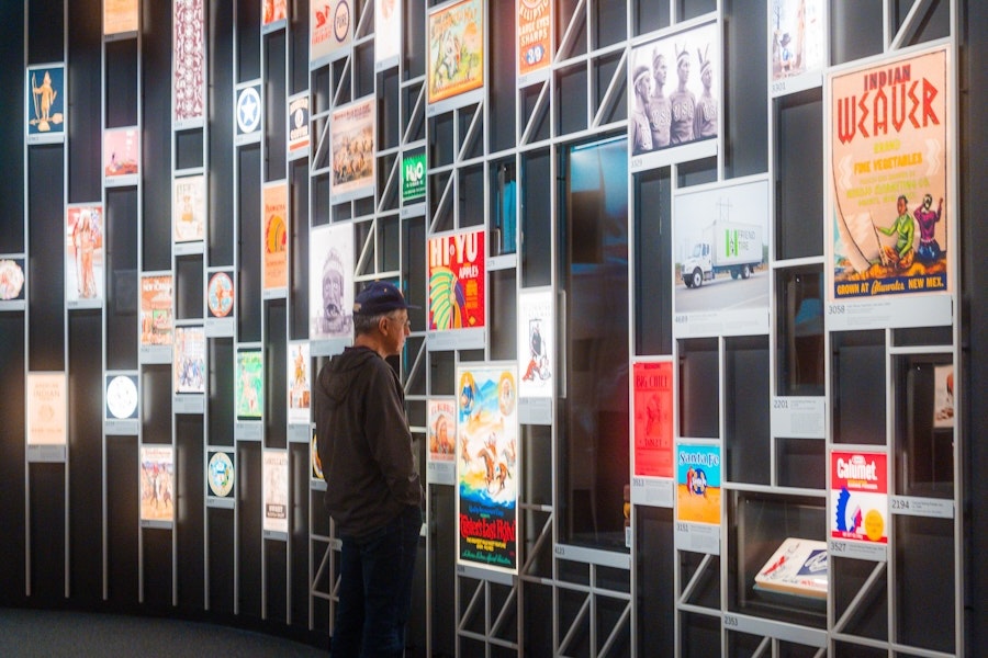 Man viewing a wall display of illuminated posters inside the National Museum of the American Indian.