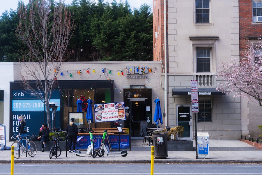 People gather outside Duke's Counter restaurant on a sunny day.