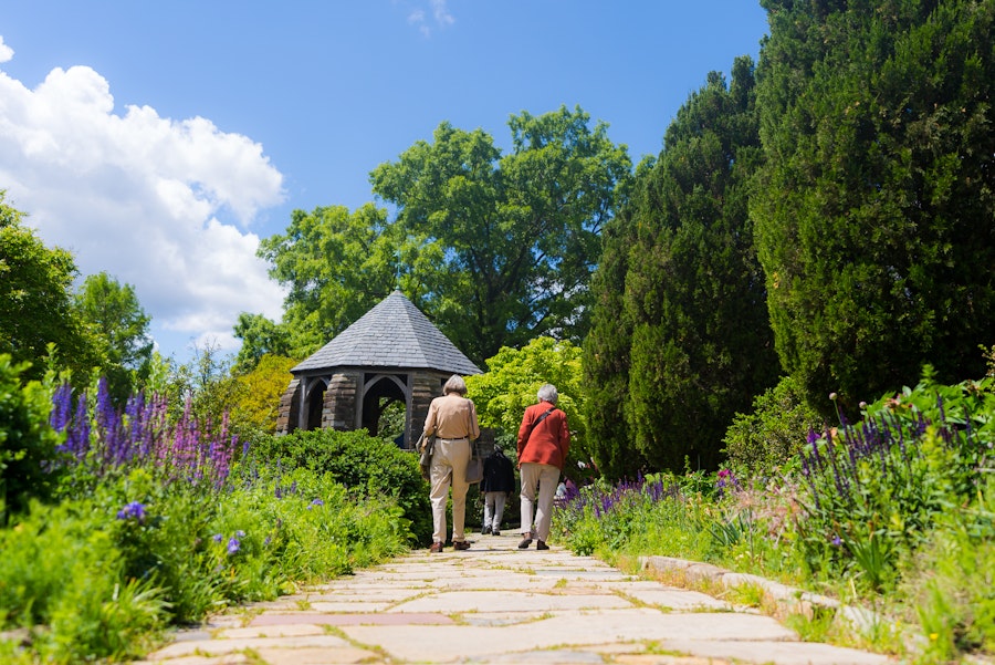 Two people walk along a path inside the Bishop's Garden at the Washington National Cathedral.