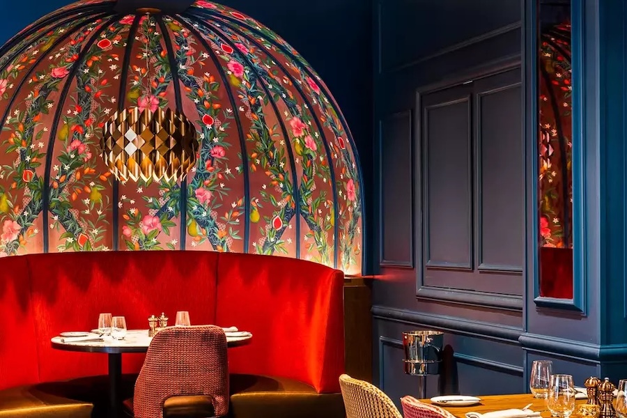 The interior of a modern dining room, focused on a table with an ornate backdrop.
