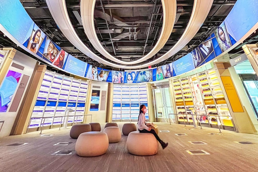 child sitting in the middle of an oval room with screens on all sides of the wall