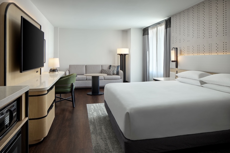 An elegant hotel room with a king sized bed in the center. 