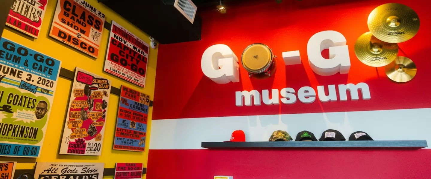 A vibrant display at the Go-Go Museum in Washington, DC, featuring bold signage, cymbals, and vintage concert posters.
