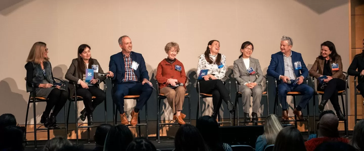 A stage of professional panelists smiling and laughing. 