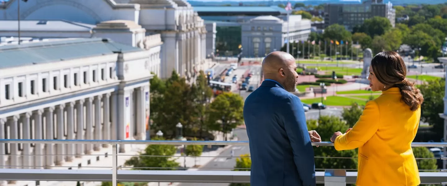 Two people looking out on Union Station with cars below 