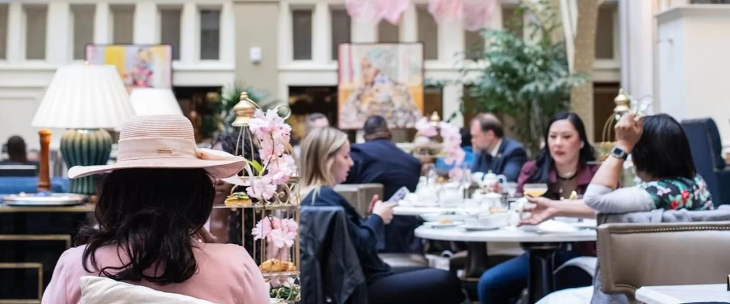 An elegant hotel lobby filled with folks enjoying afternoon tea. 