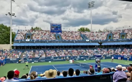 Tennis match in progress at the Citi Open with a crowd of spectators in the stands at the venue in Washington, DC.
