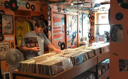 A customer browses vinyl records in a colorful store decorated with records and flyers.