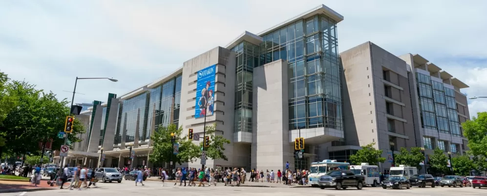 The exterior of the Walter E. Washington Convention Center on a bright day with crowds walking along the street.